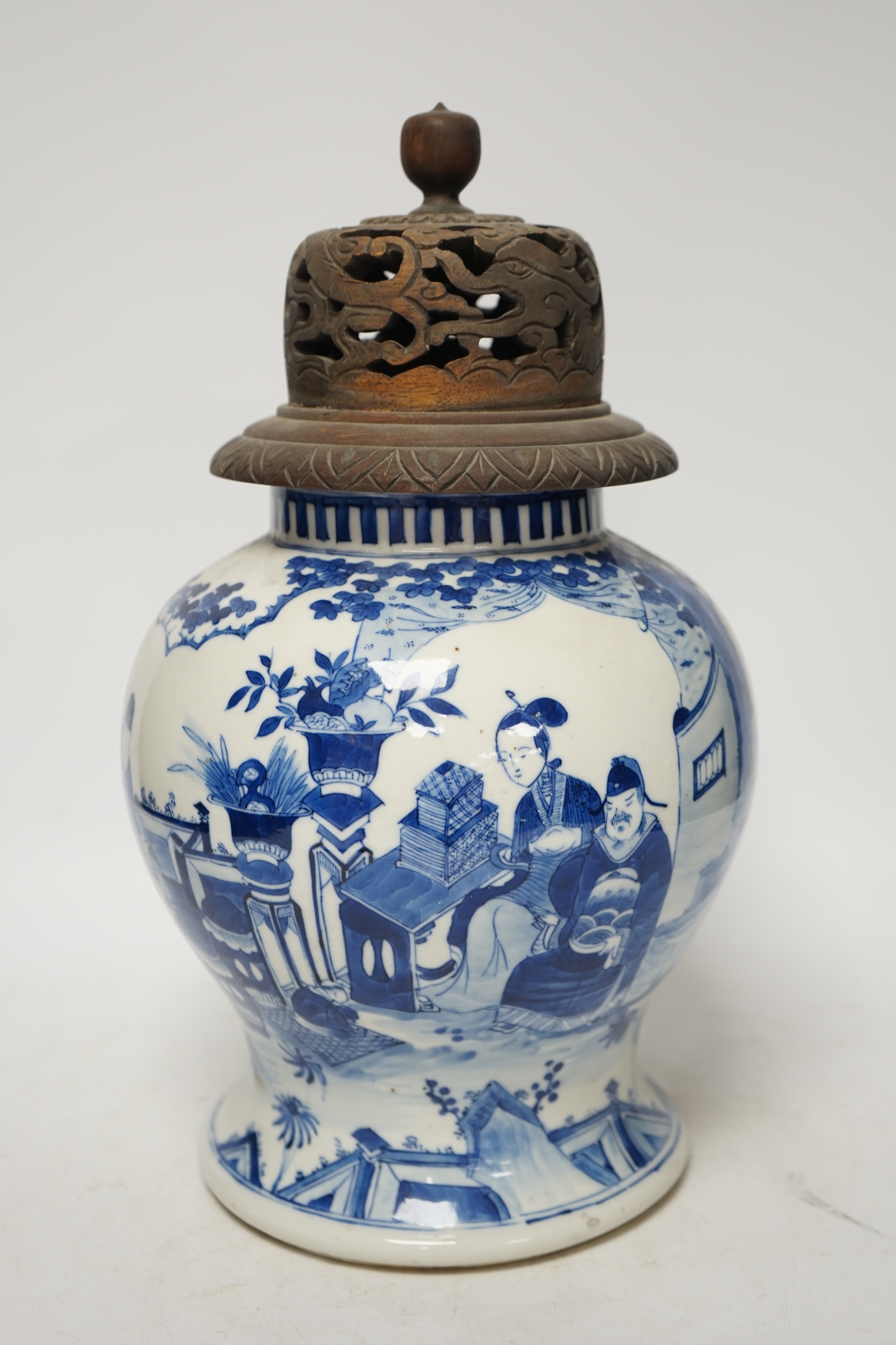A 19th century Chinese blue and white baluster jar, painted with a dignitary and attendants at a table with objects in a garden setting, wood cover, 35cm. Condition - good